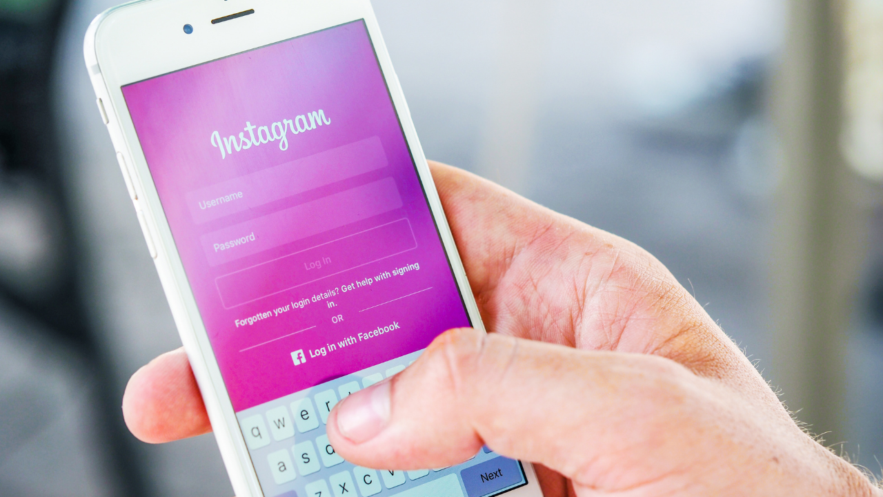 Mão masculina segurando um celular com o Instagram na tela